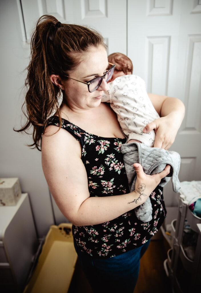 A tender moment captured during a fresh 48 photography session, with a mother holding her newborn close in a soft-lit room.