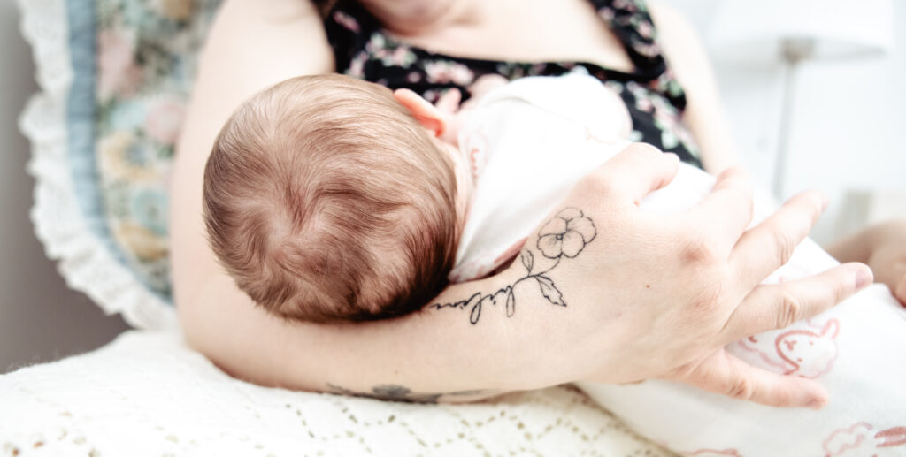 Fresh 48 photography image showing a newborn nursing in their mother’s arms, highlighting raw connection and natural postpartum moments.