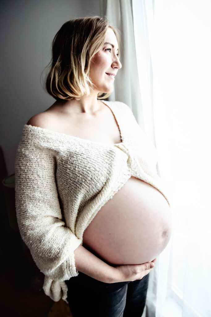 Soft natural light fills the room during an at home maternity photoshoot in Edmonton, highlighting the beauty of pregnancy.