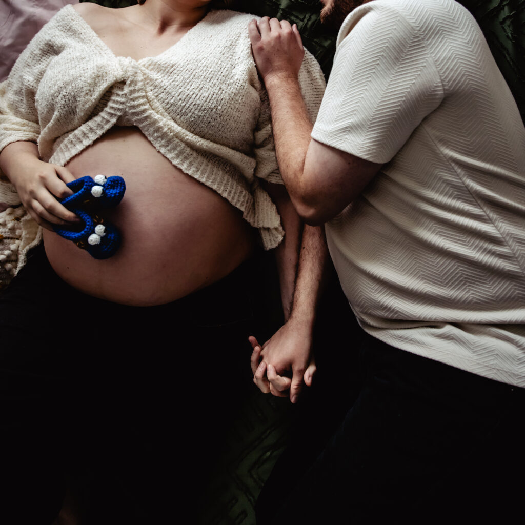 Expecting parents during their at home maternity photos in Edmonton, holding hands and cherishing quiet moments before baby arrives.