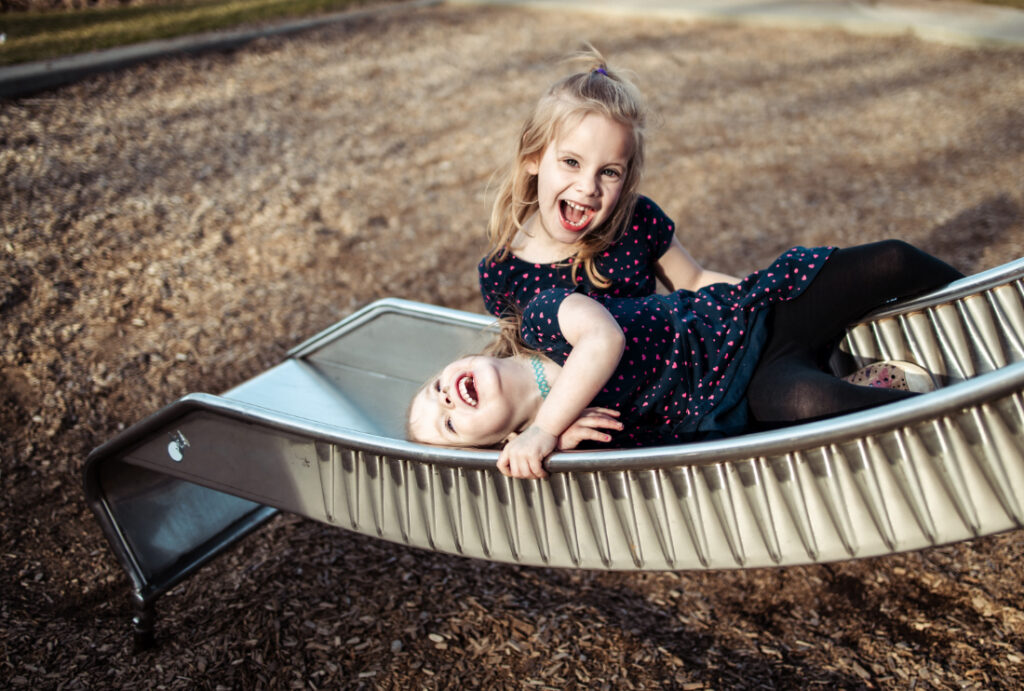Children laughing together on a playground structure, captured during a family session at one of the playful photoshoot locations Edmonton families love.