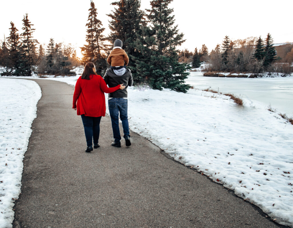 A family walking together along a snowy paved path during a winter session at one of the peaceful photoshoot locations Edmonton families enjoy year round.