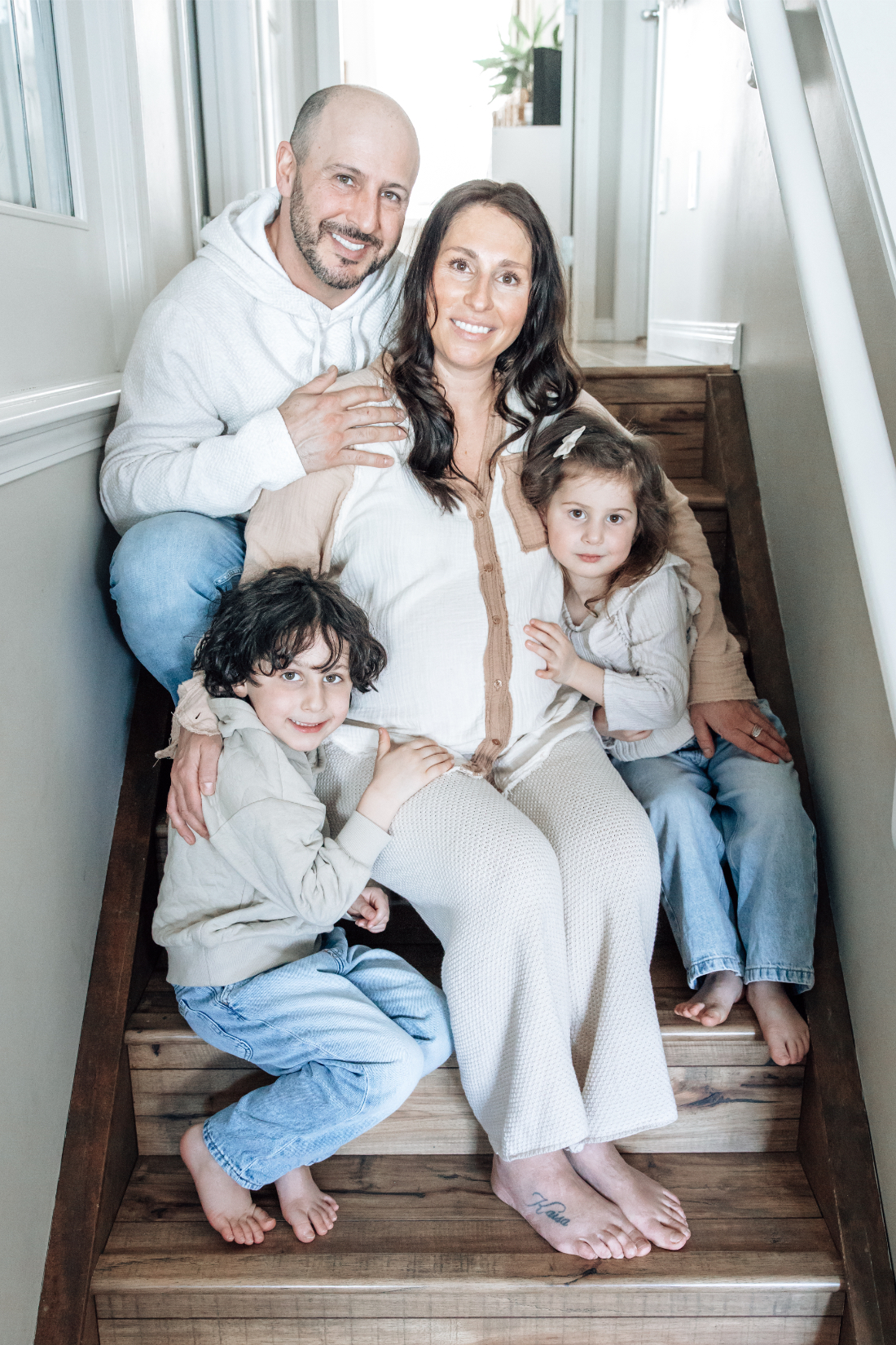 Family seated together on wooden stairs in an Alberta home, showcasing warmth and natural lifestyle photography