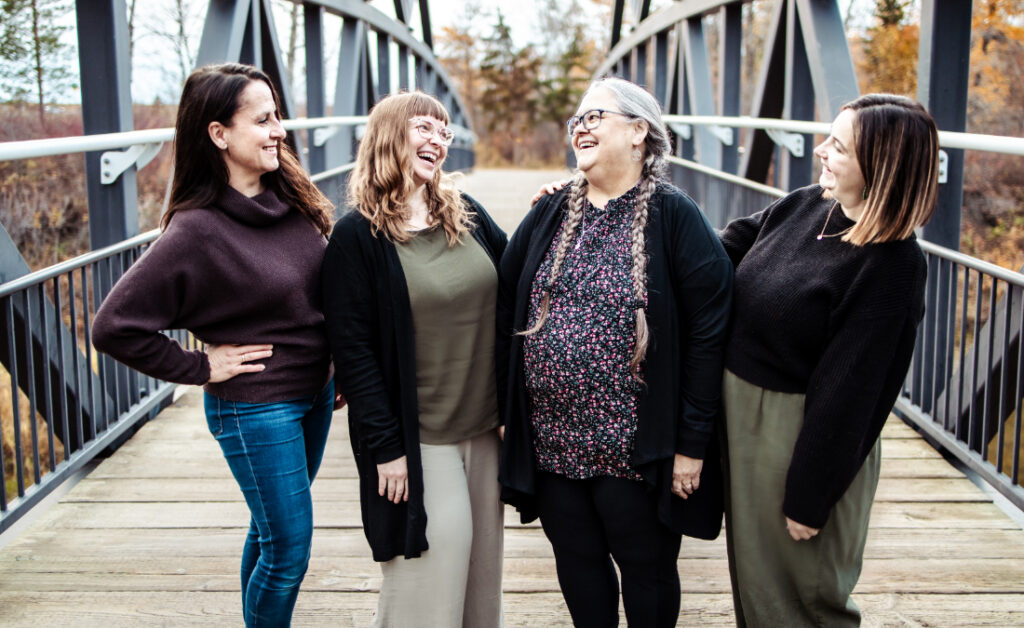 Four birth support providers share a laugh on a pedestrian bridge during a community portrait session.