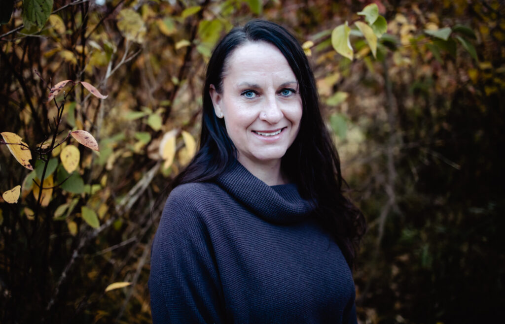 Portrait of a birth worker surrounded by autumn leaves, part of the network of Edmonton doulas and midwives supporting growing families.