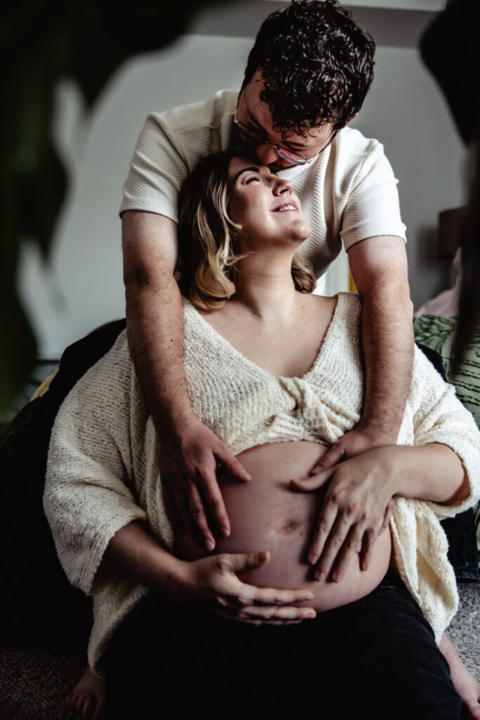 Pregnant couple share a quiet moment together while connecting with their baby before birth, reflecting the personalized care offered by Edmonton doulas and midwives.