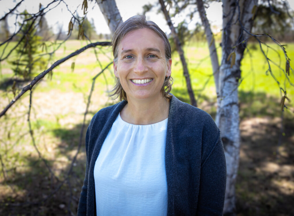 Professional headshot of a birth worker photographed outdoors in a natural setting.