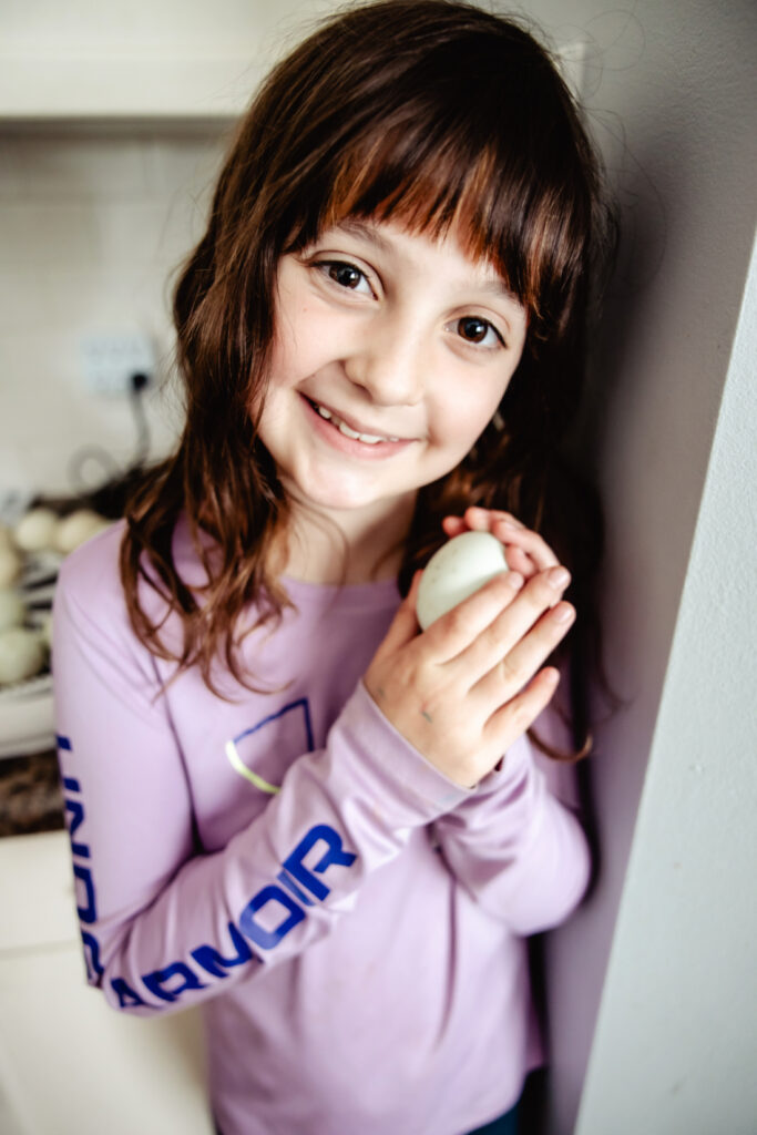 Young girl holding a duck egg while waiting for hatch day to arrive