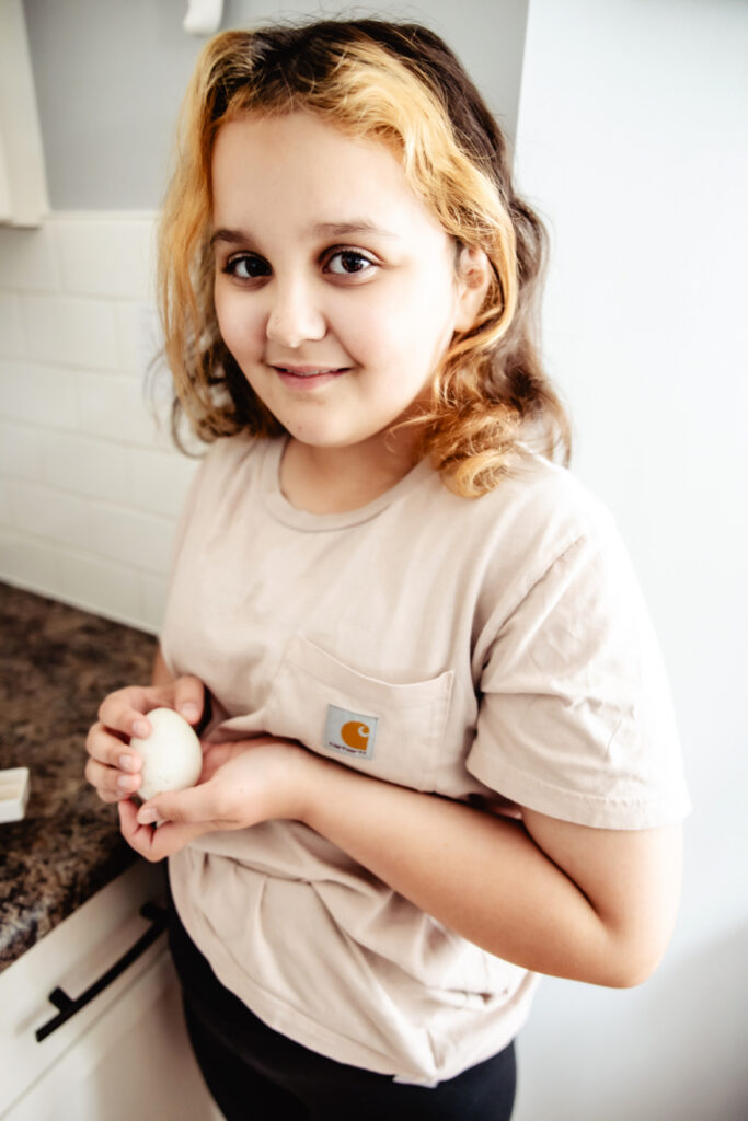 Portrait of a child carefully holding a duck egg during a family incubation project